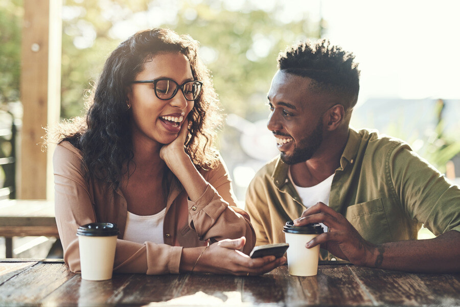 A couple checks their cashback checking account over coffee using mobile banking.