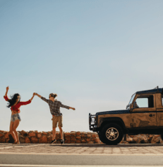 Happy couple dancing by a car